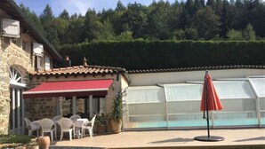 A stone building with a red awning, outdoor seating, a pool, and a greenhouse. - Le Paradis Perdu - SAINT-IGNY-DE-VERS (SAINT-IGNY-DE-VERS)