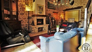 A cozy living room with a stone wall, a fireplace, leather furniture, and a chandelier. - Le Paradis Perdu - SAINT-IGNY-DE-VERS (SAINT-IGNY-DE-VERS)