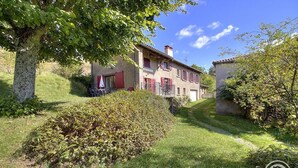 A traditional two-story house with a garden, a red umbrella, and a small outdoor seating area. - Gîte de Haute Combe - JULIENAS (JULIENAS)