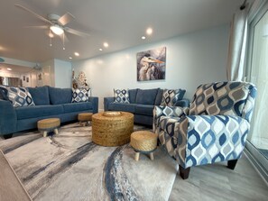 Ein modernes Wohnzimmer mit einem blauen Sofasitzgruppe, einem gemusterten Sessel und einem gewebten Couchtisch.