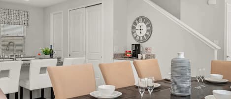 Comedor con una mesa de madera oscura dispuesta para cuatro, platos blancos y copas de cristal.