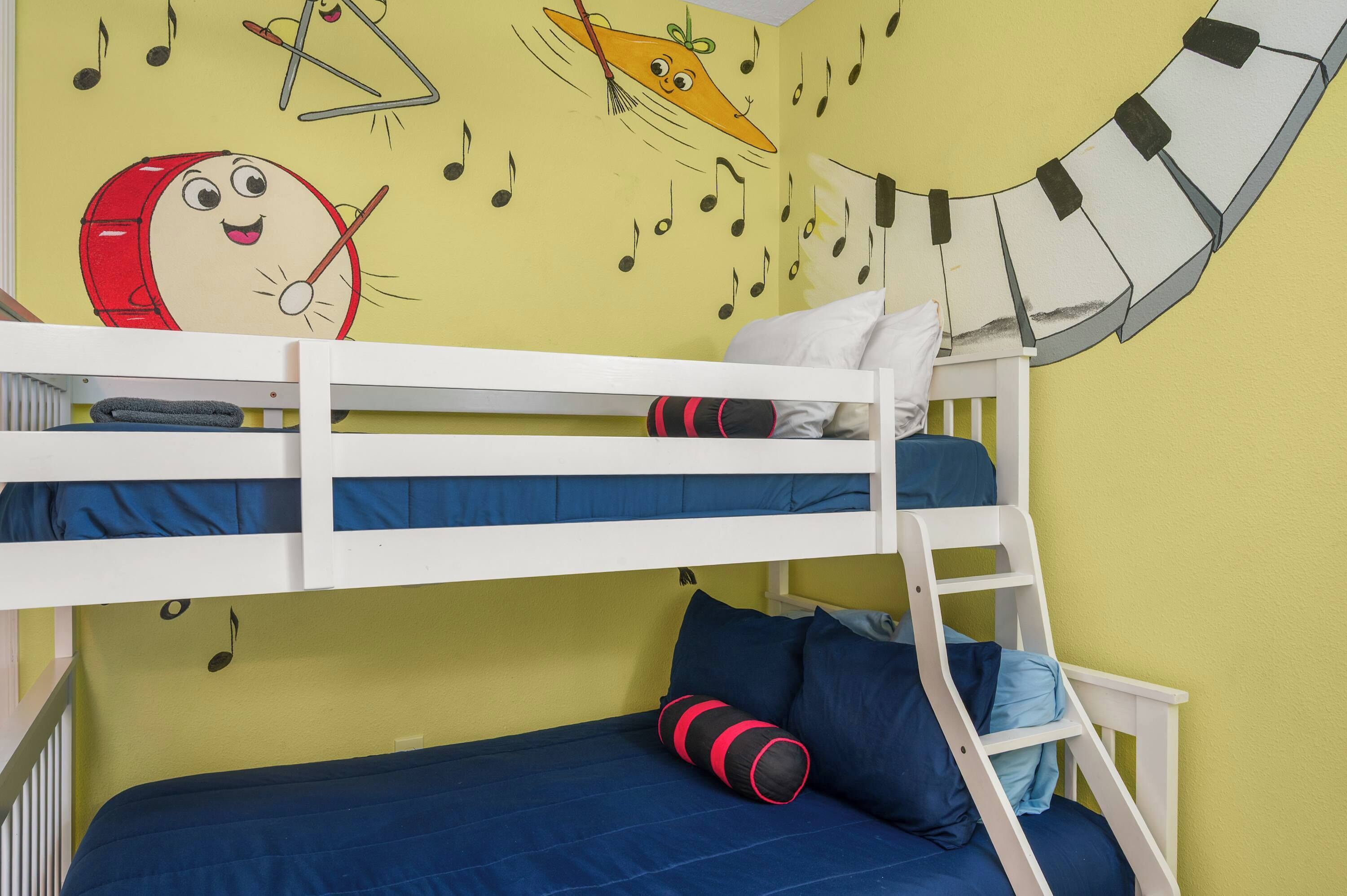 A bunk bed with a cartoon character on the wall, a ladder, and a blue mattress.