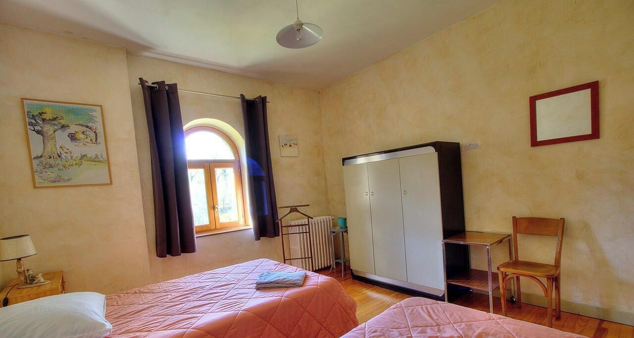 Une chambre avec deux lits, un radiateur, une armoire, une chaise et un tableau au mur.