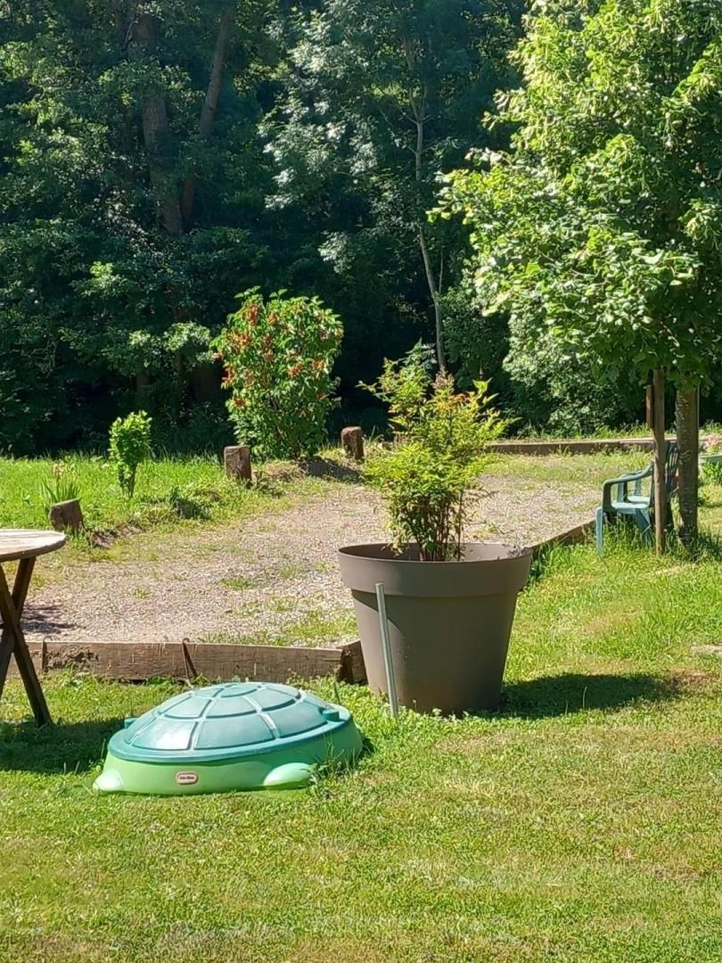 Een gazon met een grote plantenbak, een klein tafeltje en een groene stoel.
