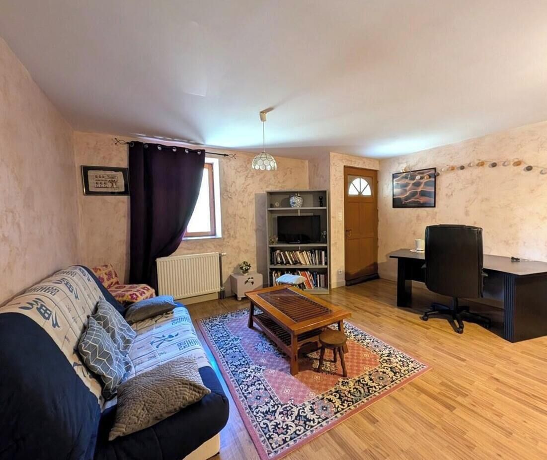 Una sala de estar con un sofá, una mesa de centro de madera, un mueble para la televisión y un escritorio con una silla.