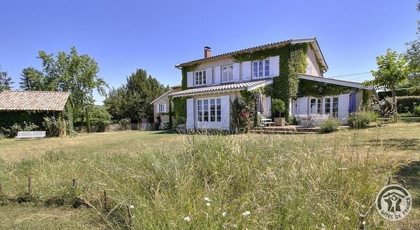 A two-story house with a garden in front, a small shed, and a clear blue sky. - La Grande Maison sur la Colline - Boistrolles (VAL D'OINGT)