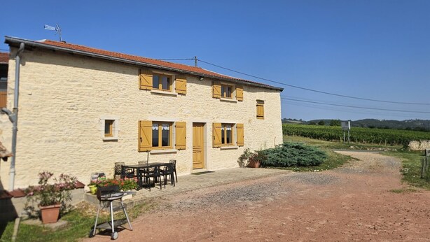 A two-story stone building with wooden shutters, a gravel driveway, and a vineyard in the background. - Gîte Passot - MORANCE - Gîte (MORANCE)