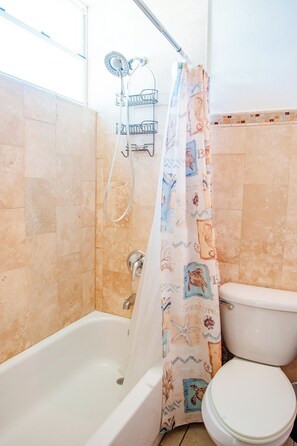 A bathroom with a bathtub, toilet, and shower curtain with a sea-themed design. - El Combate Oceanview Condos (Boquerón)