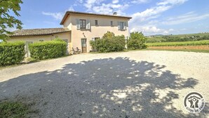 Une maison à deux étages avec une allée en gravier, un vélo et un jardin bien entretenu.