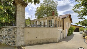 A building with a stone wall, a covered patio with chairs, and a garage.