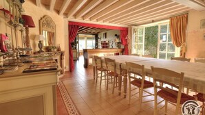 Un comedor con una mesa larga y sillas, techo de madera y vistas al exterior a través de amplios ventanales.