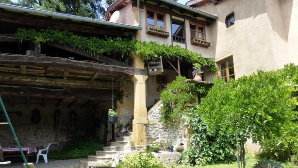 Ein rustikales Gebäude mit einer Steintreppe, einer Veranda und einem Garten mit Kübelpflanzen.
