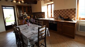 Une cuisine avec des meubles de rangement en bois, un pare-feu en carreaux et une table à manger accompagnée de chaises.