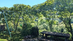 Un parc équipé d’une aire de jeux avec des balançoires, d’une table de pique-nique et d’un espace barbecue.