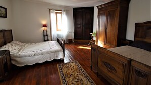 Une chambre à coucher avec deux lits en bois, une table de chevet, une commode et une fenêtre avec des rideaux.