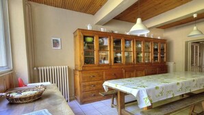 Ein Essbereich mit einem Holzkabinett, einem Tisch mit Tischdecke und einer Pendelleuchte.