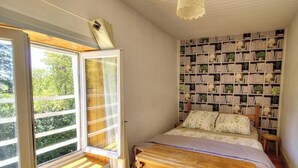 Ein Schlafzimmer mit großem Fenster, einer Bücherwand und einem Bett mit Holz Kopfteil.