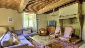 Ein Wohnzimmer mit Sofa, Sesseln, Couchtisch, Kamin und Fernseher.