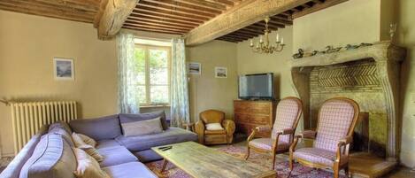 A living room with a sofa, armchairs, a coffee table, a fireplace, and a television.