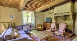Ein Wohnzimmer mit Sofa, Sesseln, Couchtisch, Kamin und Fernseher.