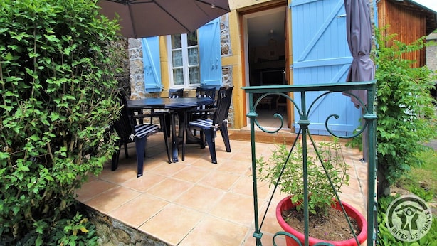 An outdoor patio with a table and chairs, a potted plant, and a stone wall. - Moulin La Chavanne - POULE-LES-ECHARMEAUX (POULE-LES-ECHARMEAUX)