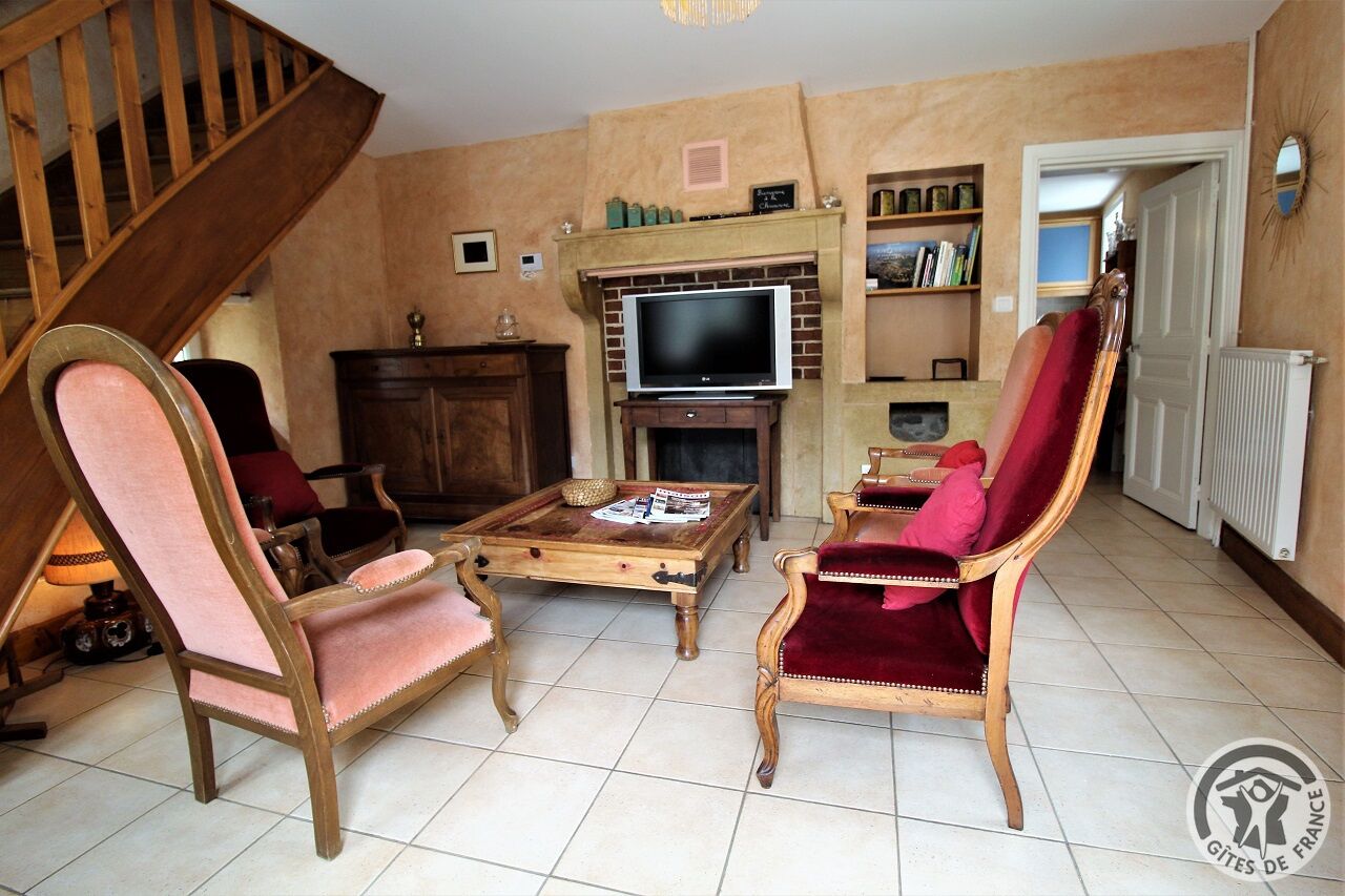Una sala de estar con escalera de madera, televisor, chimenea y estantería.