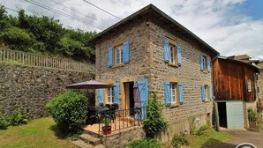 A stone house with blue shutters, a patio with outdoor furniture, and a stone wall. - Moulin La Chavanne - POULE-LES-ECHARMEAUX (POULE-LES-ECHARMEAUX)