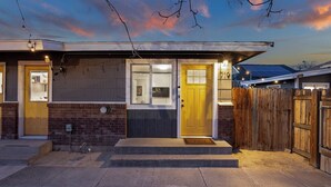 A modern two-story house with a brick facade, a yellow front door, and a wooden fence. - #719 Cozy Midtown Reno Retreat (Reno)