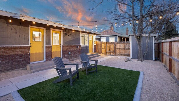 A backyard with a patio, two Adirondack chairs, a wooden fence, and string lights. - #719 Cozy Midtown Reno Retreat (Reno)