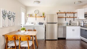 A modern kitchen with white appliances, wooden chairs, and a dining table. - #719 Cozy Midtown Reno Retreat (Reno)