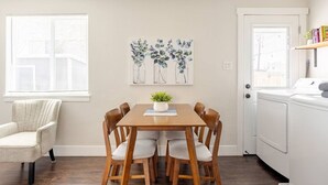 A dining area with a wooden table and chairs, a potted plant, and a wall-mounted painting of eucalyptus branches. - #719 Cozy Midtown Reno Retreat (Reno)