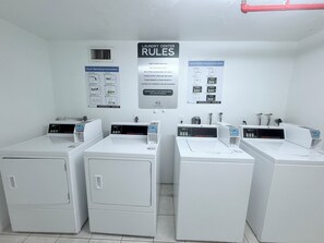 A laundry center with four front-loading washing machines, operating instructions, and a vent on the wall. - Walk to Beach! Spacious Family Condo w/ Pool, Gym & Parking (Sunny Isles Beach)