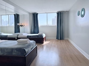 Ein Hotelzimmer mit einem großen Bett, einem kleineren Bett, einem Spiegel, einer Kandelaber und Blick auf die Stadt.
