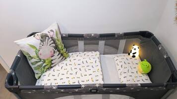 Ein Babybett mit einem Zebra-Kissen, einem Panda-Kissen und einem grünen Spielzeug.