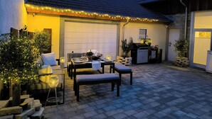 An outdoor patio with a dining table set for two, a barbecue grill, and a stone wall. - Apartment D&Y upper floor (barrier-free) (Ubstadt-Weiher)