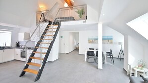 A modern apartment with a staircase connecting two floors, a kitchen with white cabinets, a dining area with a table and chairs, and a living room with a sofa and a lamp. - Apartment D&Y upper floor (barrier-free) (Ubstadt-Weiher)