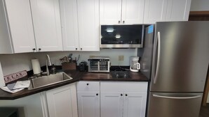 A kitchen with white cabinets, a stainless steel refrigerator, a microwave, and a coffee maker. - LAKEFRONT 2-bedroom Chateau Getaway at Whitecap Mountains Resort Unit 4 (Upson)