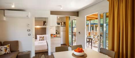 A modern, open-plan living space with a dining area, kitchen, and a view of the outdoors.