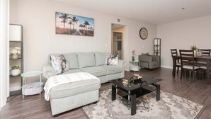 A living room with a sofa, coffee table, and dining area with chairs. - Hollywood 2BR Apt with Rooftop Pool & Cityscape (Los Angeles)