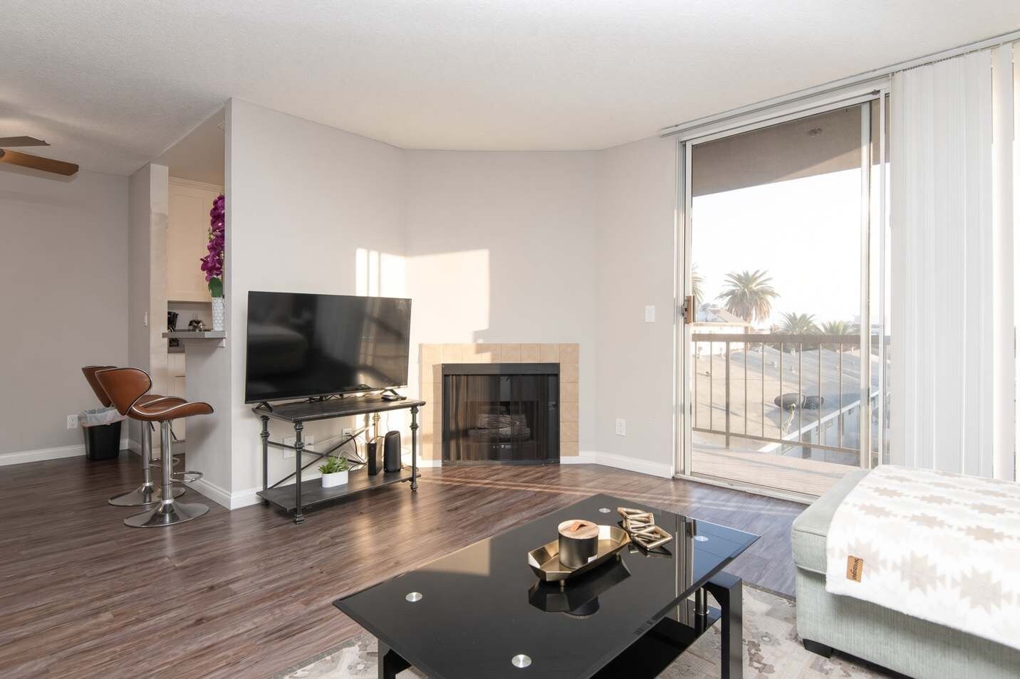 A modern living room with a flat-screen TV, a fireplace, a dining table, and a sofa.