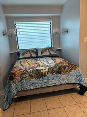 A bedroom with a bed, a window with blinds, and two wall-mounted lamps. - Oceanfront Studio with resort amenities (Myrtle Beach)