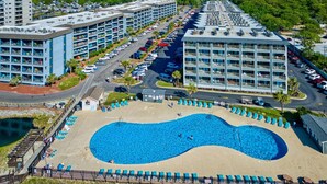 A resort with a large swimming pool, multiple hotel buildings, and a parking area. - Oceanfront Studio with resort amenities (Myrtle Beach)