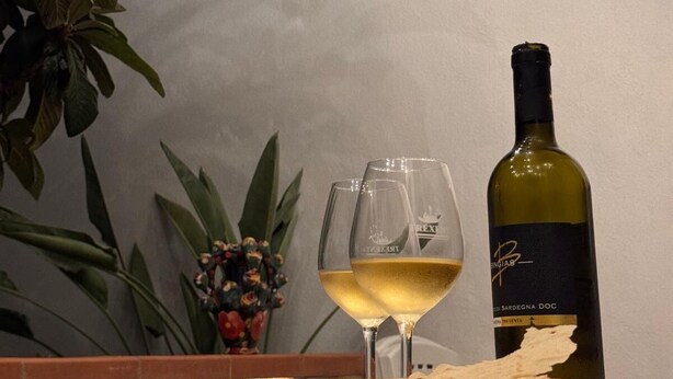 A table with two wine glasses, a bottle of wine, and a bowl of bread on a tablecloth. - Janas Holiday House: in the heart of southern Sardinia. Sea and real Sardinia. (assemini)