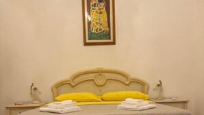 A bedroom with a bed, two bedside tables, a nightstand, a framed artwork, and a tiled floor. - Janas Holiday House: in the heart of southern Sardinia. Sea and real Sardinia. (assemini)