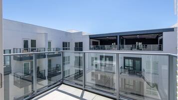 A modern building with a glass balcony, multiple windows, and a flat roof.