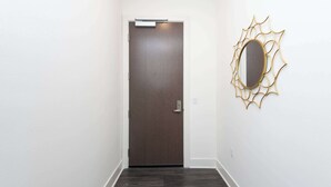 A hallway with a dark wooden door and a wall-mounted mirror with a gold frame.