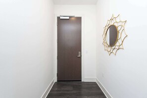 A hallway with a dark wooden door and a wall-mounted mirror with a gold frame.