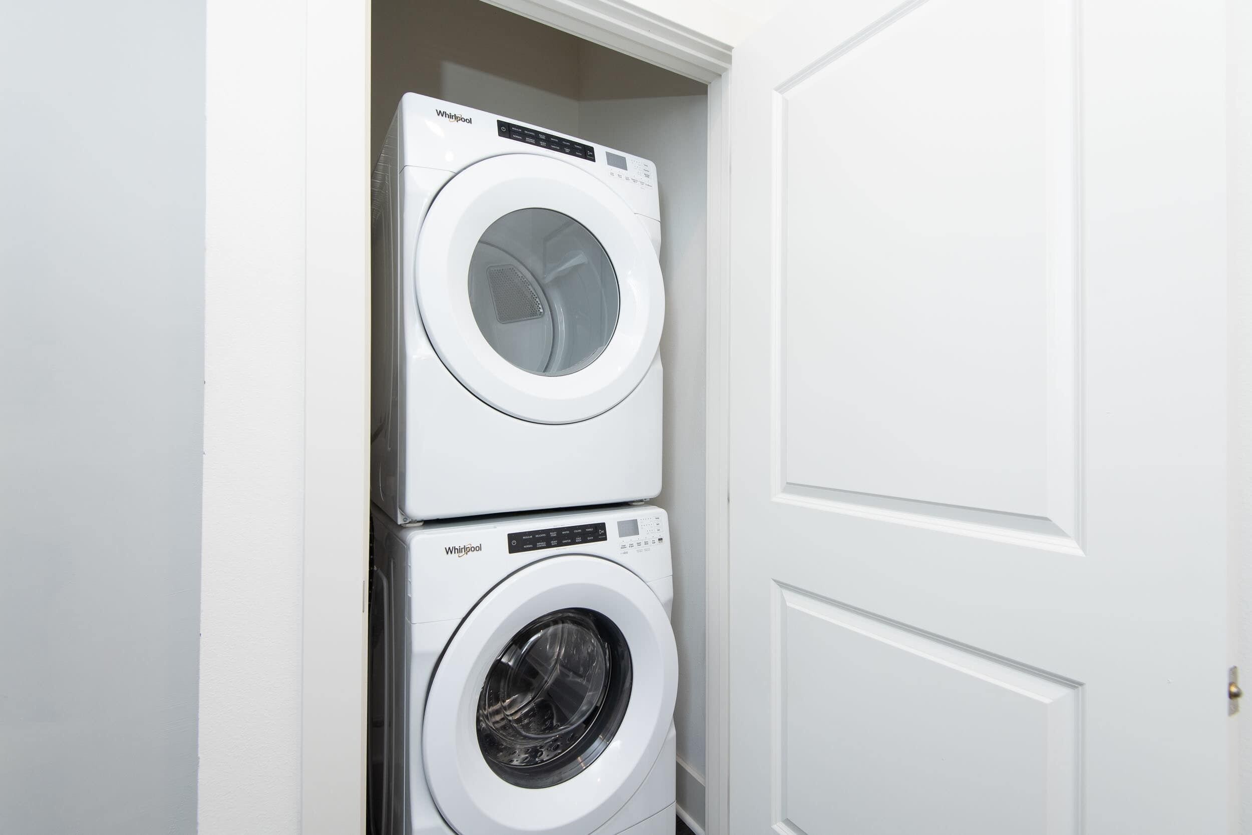 A stacked washer and dryer unit in a white-walled room.