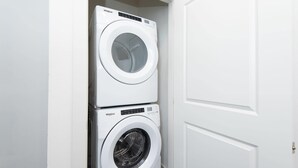 A stacked washer and dryer unit in a white-walled room.