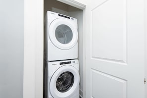 A stacked washer and dryer unit in a white-walled room.